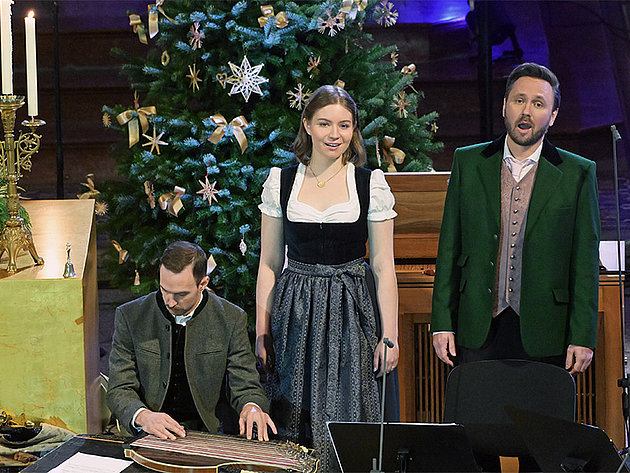 Die Musiker Rafael Fingerlos, Anja Mittermüller und Fabian Steindl bei einem Weihnachtskonzert 2025 er Salzkammergut Festwochen Gmunden vor einem geschmückten Christbaum, die zwei Männer in Anzug und Trachtenjacke, die Frau in Dirndl, Fabian Steindl spielt Zither.