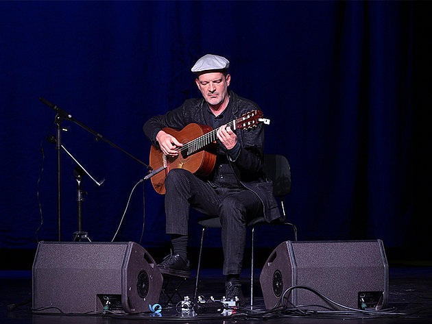 Gitarrenvirtuose und Komponist Wolfgang Muthspiel spielt akustische Gitarre sitzend auf der Bühne im Stadttheater Gmunden während der Salzkammergut Festwochen am 25.05.2025